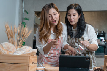 View of Asian women wearing apron and learning process to bake the Bakery from tablet