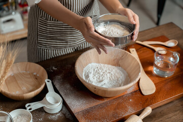View of the hand of asian women baker Sifting Bread Flour before the process of Kneading Dough.