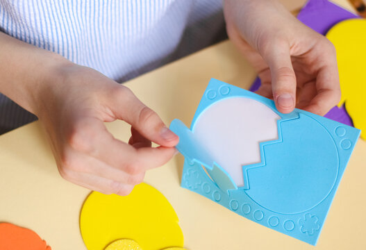 The hands of a caucasian teenage girl peel off with their fingers a sticker of a blue shell