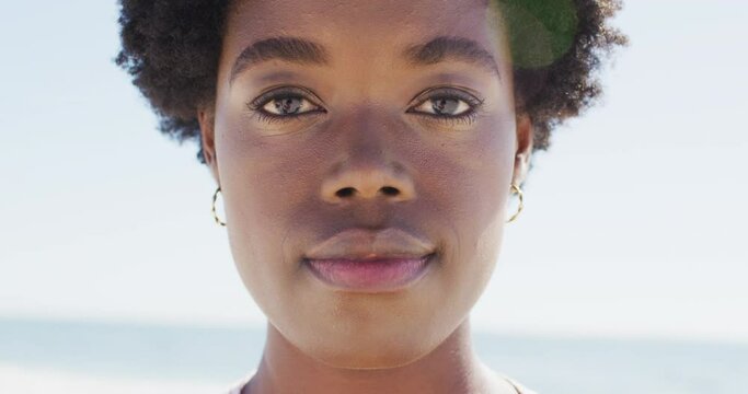Video of face of happy african american woman looking at camera on beach
