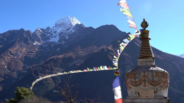 A chorten or stupa in the Himalayan Mountains with prayer flags blowing in the wind.