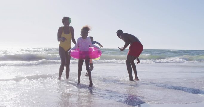 Video of happy african american family having fun o beach