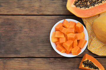 Tasty whole and cut papaya fruits on wooden table, flat lay. Space for text