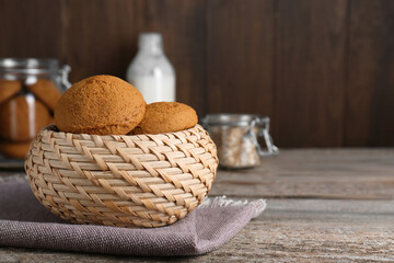 Wicker basket with delicious oatmeal cookies on wooden table. Space for text