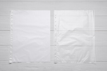 Punched pockets on white wooden table, flat lay. Space for text