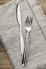 Fork, knife and napkin on wooden table, top view. Stylish shiny cutlery set