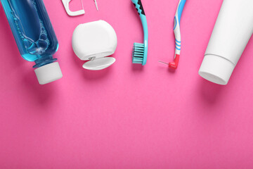 Flat lay composition with dental floss and different teeth care products on pink background, space...