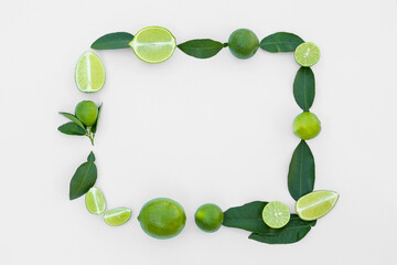 Frame made of fresh ripe limes and green leaves on white background, flat lay. Space for text