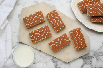 Tasty sponge cakes and milk on white marble table, flat lay