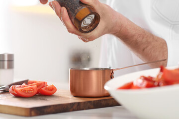 Professional chef adding pepper into scoop at table in kitchen, closeup