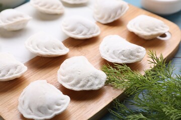 Fototapeta na wymiar Raw dumplings (varenyky) and ingredients on light blue table, closeup
