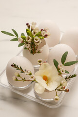 Easter eggs and beautiful flowers on white marble table, closeup