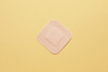 Contraceptive patch on yellow background, top view