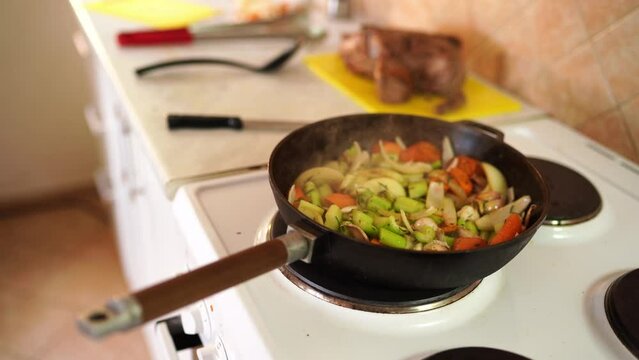 Steam rises over chopped vegetables stewing in a pan