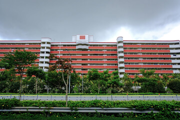 Long block of HDB flat building in front of expressway lined with trees; wide angle