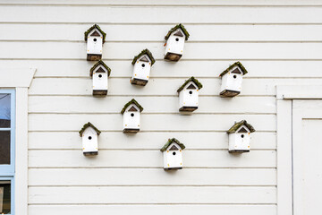 Collection of white wooden bird houses on the side of a white building
