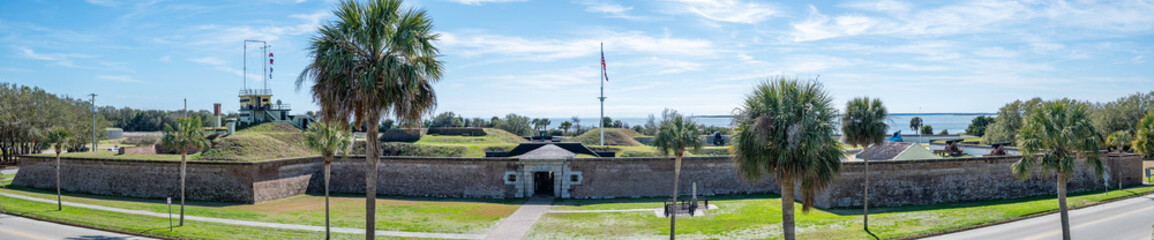 Panorama of Fort Moultrie, showing the front entrance, American flag, cannon on the ramparts, and Charleston Harbor in the background.