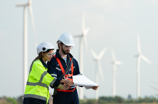 Man and female engineer stationed at the Natural Energy Wind Turbine site. with daily audit tasks of major wind turbine operations that transform wind energy into electrical electricity