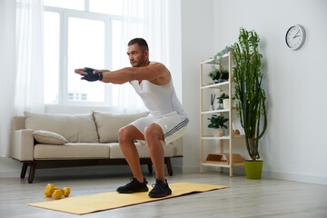Fototapeta na wymiar Man sports home training on the floor on a mat with dumbbells, exercises for muscle growth, pumped up man fitness trainer exercises at home, the concept of health and beauty of the body