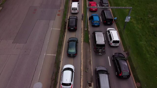 Aerial view of cars lining up to enter a railway . Tilting up revealing the train tracks and impressive mountain valley. Switzerland