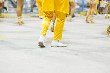 legs of a samba dancing, with yellow pants and white shoes at the sambodromo da marques de sapucai in Rio de Janeiro.