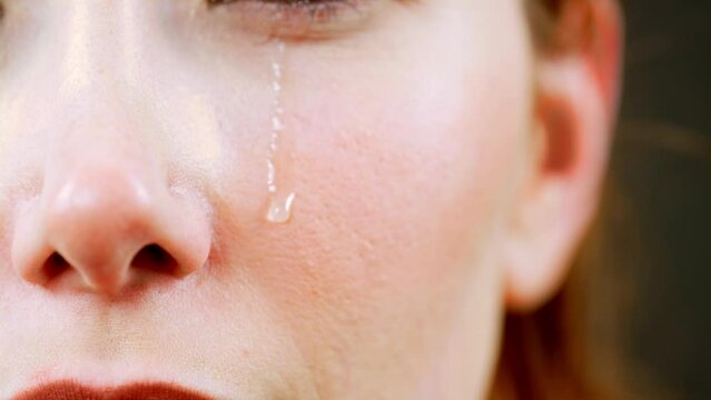 The video footage that shows the moment when tears flow down the face of a crying woman in a macro shot.