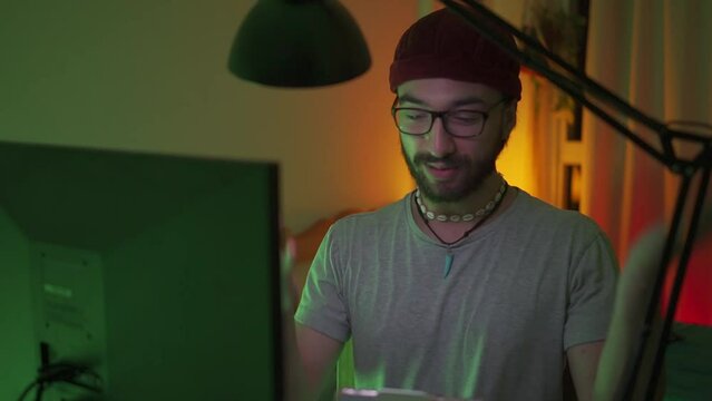 Young latin man with a beanie happily greeting his channel viewers in a streaming, looking at the camera