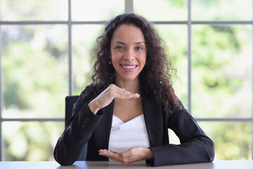 Attractive professional latin female in classic suit show protecting something on table....