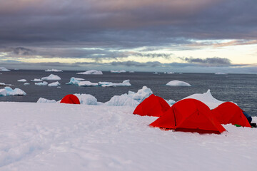 Remote winter campsite on Portal Point in Antarctica overlooking bay with icebergs