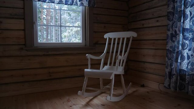 A rocking chair inside a log cabin during winter.