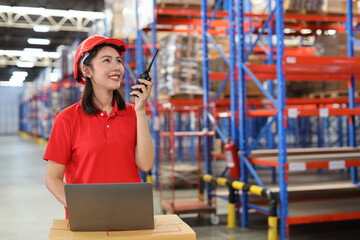 Warehouse workers young asian woman using computer and walkie talkie radio while controlling stock and inventory in retail warehouse logistics, distribution center