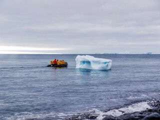 Tourism in Antarctica, as cruise ship passengers ride in an inflatable boat past an iceberg floating near the beach of Paulet Island.