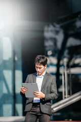Fototapeta premium Asian businessman using a tablet and laptop on a bench in the city