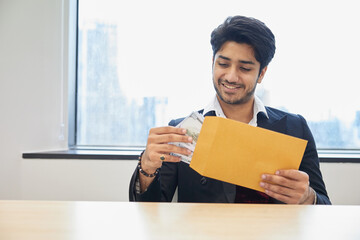 businessman receiving bonus money from envelope in the office