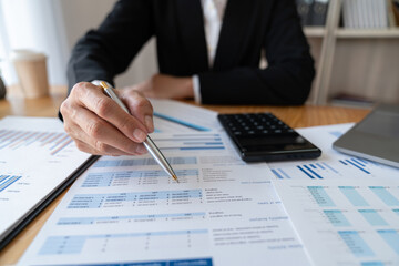 Asian businesswoman calculating income-expense and analyzing tables Real estate investment figures graph and growth of the company The concept of monetary and tax systems.