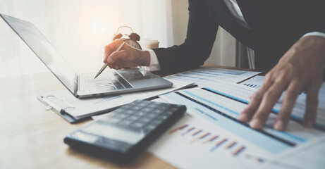 Financial analyst or Asian businesswoman analyzing and compare detailed financial reports, taxes, marketing on laptop and various chart documents, business meeting concept, accounting