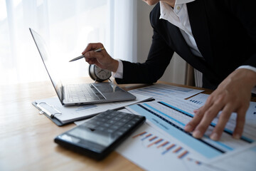 Financial analyst or Asian businesswoman analyzing and compare detailed financial reports, taxes,...