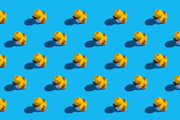Cute yellow rubber ducks in rows on blue background