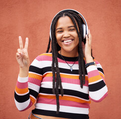 Portrait, headphones and black woman with peace sign isolated on orange wall for gen z music or...