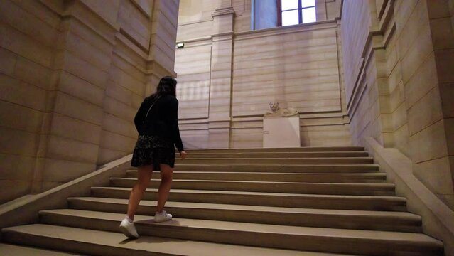 Slow Motion Of A Woman Walking Up On Stairs Inside The Louvre Museum In Paris, France. low angle, following