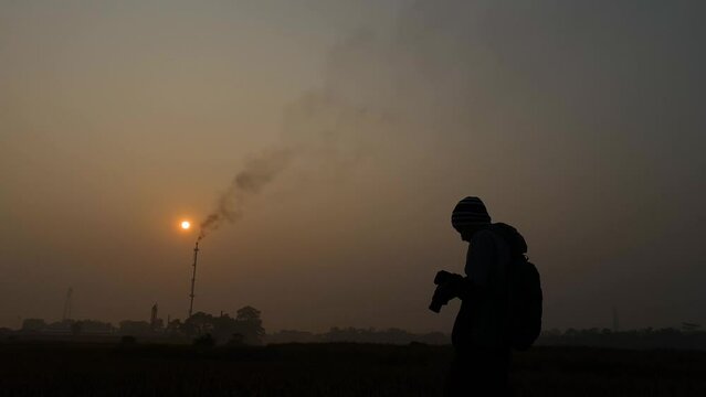 Cinematic wide view of photographer taking photos of Industrial gas plant area. Silhouette