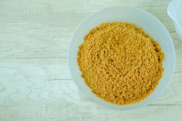 Brown sugar from natural cane juice on a white bowl, flat layout, copy space