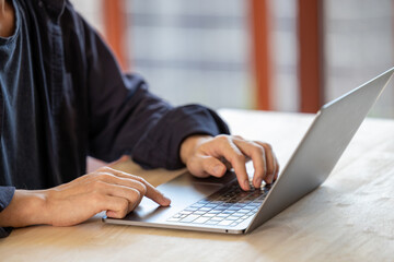 Businessman working on laptop computer on wooden table at office. Business man hands typing on laptop, online working, surfing the internet.