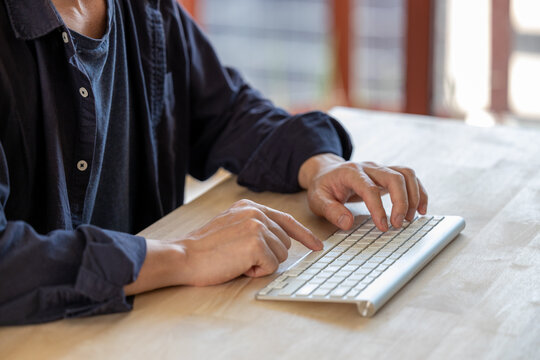 Businessman working on keybord computer on wooden table at office. Business man hands typing on laptop, online working, surfing the internet.