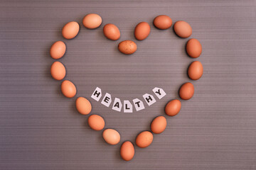 Eggs placed in the shape of a heart with text smiling to communicate that they are healthy to the heart . View from top