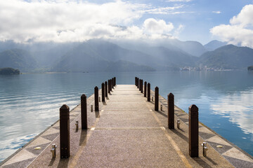 Large blue lake surrounded by mountains with pier in the morning at sun moon lake of Taiwan