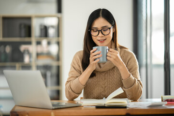 Asian businesswoman sitting and drinking coffee in office