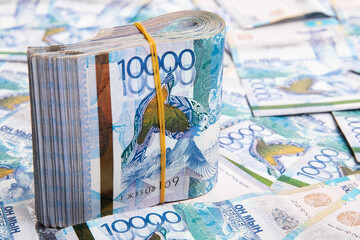 A pack of 10000 banknotes of Kazakhstan tenge, against the background of spread out Kazakhstani money.