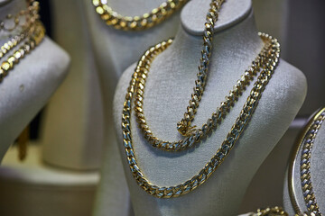 Close up of the jewelry gold necklaces ring, chains  show in  beauty retail store window display showcase background.