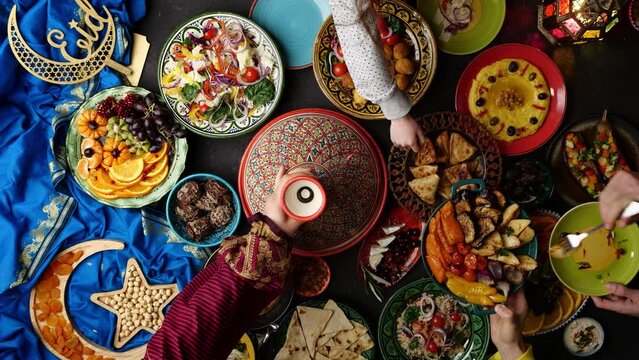 Ramadan food table. Top view of Muslim family and friends eating food on the table and celebrating the Eid holiday. Hot lamb in Moroccan tagine